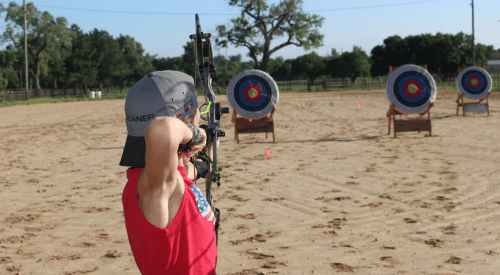 A 4-H member shoots a bow and arrow at targets at Rock Springs 4-H Camp